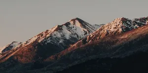 Capture of snow-capped mountains under warm evening light, showcasing winter majesty. jigsaw puzzle