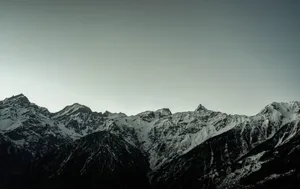 A stunning view of snow-covered mountain peaks against a gray sky, captured at dawn, showcasing nature's beauty. jigsaw puzzle