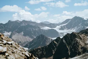 Picturesque scenery of rough rocky mountain tops covered with snow located highland under cloudy sky jigsaw puzzle