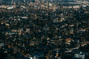 Drone view of modern multistory buildings with glowing lights located on dark streets of contemporary city at dark night time jigsaw puzzle