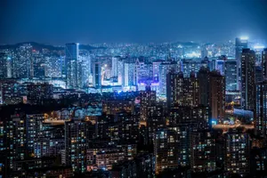 A stunning cityscape at night featuring illuminated skyscrapers and modern urban architecture under a clear sky. jigsaw puzzle