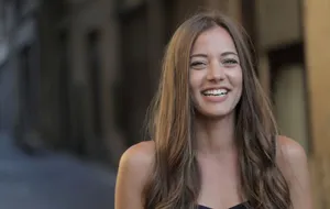 A woman with long hair smiling in an urban outdoor scene. jigsaw puzzle