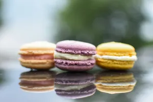 Three colorful macarons with reflections on a glossy surface, showcasing vibrant hues. jigsaw puzzle