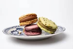 A close-up of three colorful French macarons elegantly arranged on a blue floral porcelain plate. jigsaw puzzle