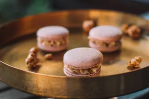 Close-up of pink macarons with nuts on a golden tray, showcasing elegant dessert presentation. jigsaw puzzle