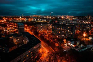 Dramatic nighttime view of a cityscape with vibrant lighting and buildings under a dark sky. jigsaw puzzle