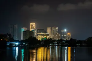 Illuminated skyline reflecting on water at night, showcasing modern architecture. jigsaw puzzle