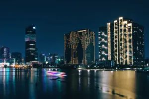 A stunning nighttime cityscape showcasing illuminated skyscrapers reflecting on calm waters. jigsaw puzzle
