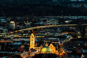Stunning evening view of Pécs, Hungary featuring illuminated churches and city lights, showcasing urban landscape charm. jigsaw puzzle