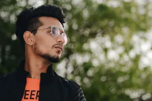 Portrait of a fashionable young man wearing glasses and a jacket outdoors with a natural bokeh background. jigsaw puzzle