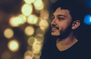 Close-up portrait of a smiling bearded man with vibrant bokeh lights at night. Warm and joyful atmosphere. jigsaw puzzle