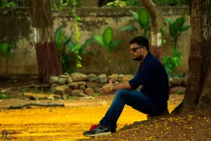 A man sits under a tree in a sunlit park, enjoying a moment of leisure. jigsaw puzzle