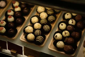 An appetizing assortment of various chocolate truffles on wooden trays under warm lighting. jigsaw puzzle