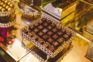 Luxurious chocolates displayed in a jeweled box on a reflective surface, providing a rich gourmet treat experience. jigsaw puzzle